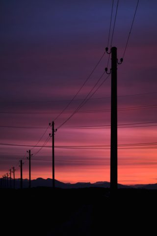 Silhouettes Poteaux et de lignes électriques se découpant sur un coucher de soleil spectaculaire rose et violet