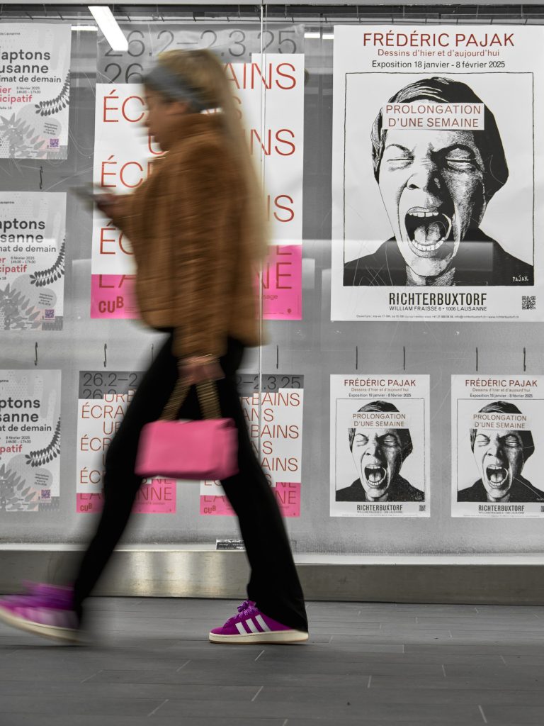 Femme en mouvement flou portant un sac rose et des baskets violettes marchant devant un mur couvert d'affiches d'exposition à Lausanne.