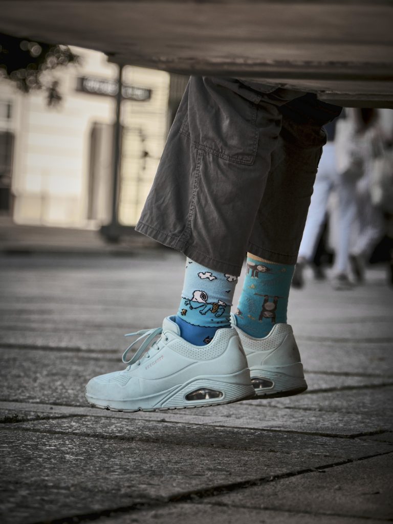 Gros plan sur les jambes d'une personne portant des baskets blanches et des chaussettes bleues fantaisie mode urbaine.