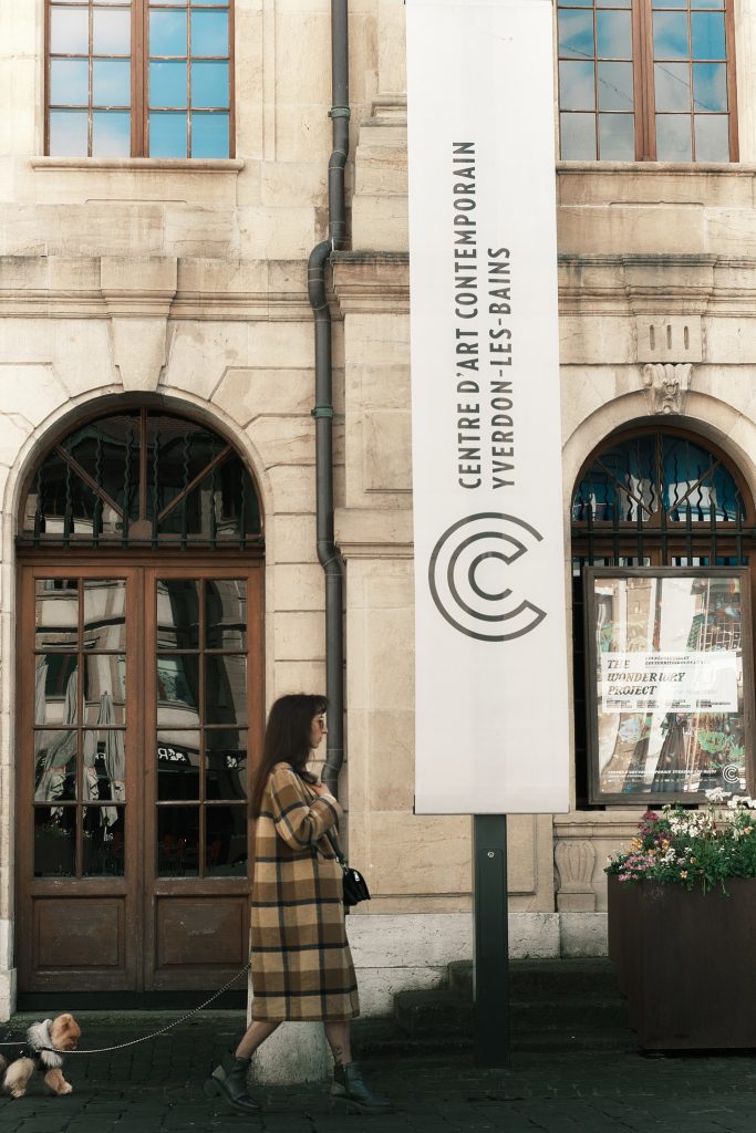 Une femme promenant son petit chien devant le bâtiment du Centre d'art contemporain à Yverdon-les-Bains.
