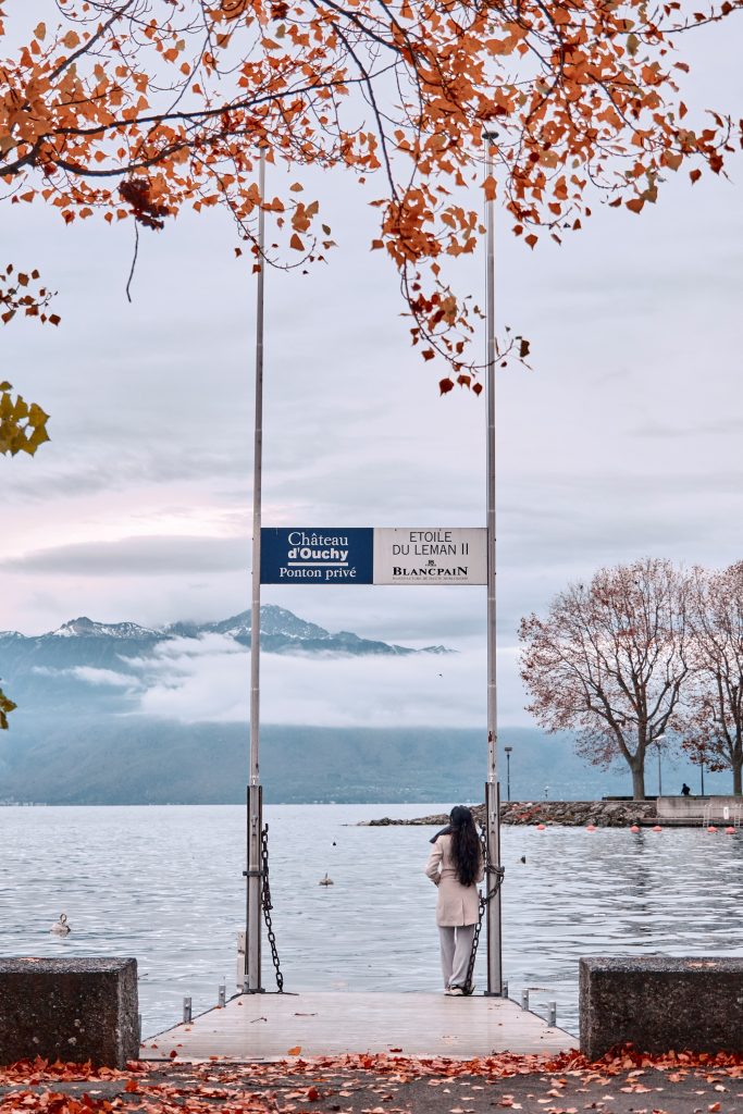 Vue automnale d'une personne sur le ponton privé du Château d'Ouchy admirant le lac Léman et les montagnes.