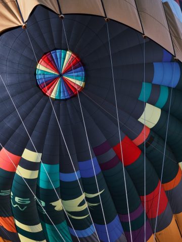 Vue en contre-plongée de l'intérieur d'une montgolfière multicolore en plein vol.