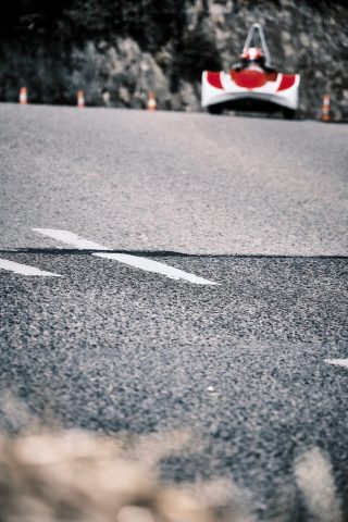 Caisse à savon rouge et blanche abordant un virage en côte sur une route asphaltée.