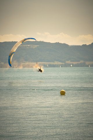 Parapentiste frôlant la surface de l'eau d'un lac lors d'un atterrissage ou d'une figure de voltige.