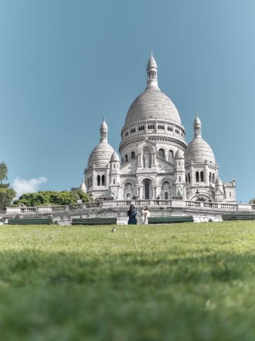 Vue en contre-plongée de la Basilique du Sacré-Cœur de Montmartre depuis la pelouse verdoyante du square.
