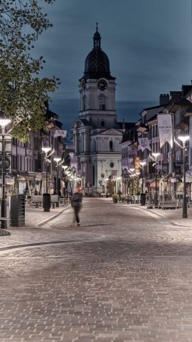 Rue pavée illuminée au crépuscule à Morges en Suisse, avec le temple en arrière-plan et les banderoles de la Fête de la Tulipe.