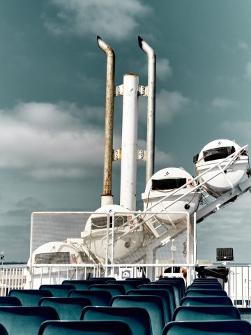 Sièges bleus vides et canots de sauvetage blancs sur le pont supérieur du ferry reliant l'île de Malte à Gozo.